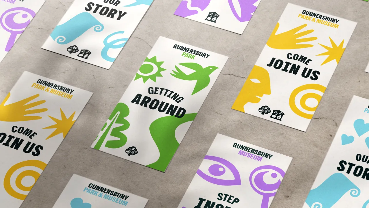 Scattered printed cards for Gunnersbury Museum and Park featuring colourful icons of hands, eyes, leaves and sun in yellow, green, blue and purple, with slogans including "Come Join Us" and "Getting Around